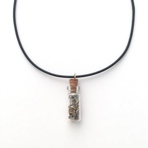 Black artistic necklace with a charm that is a small bottle with broken clock pieces in it.