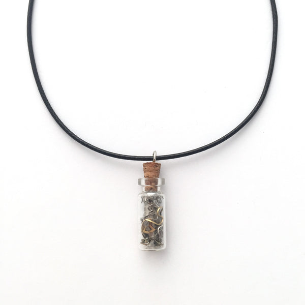 Black artistic necklace with a charm that is a small bottle with broken clock pieces in it.