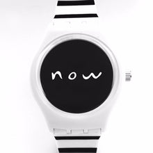 Black and white stripped watch with "now" written in white on the center of the watch's black face.